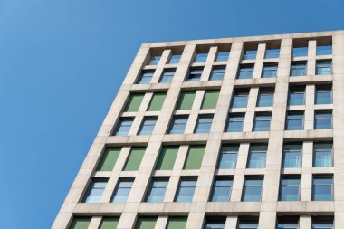 Multistorey building standing against blue sky background. Bottom view of modern skyscrapers in business district. Geometry modern of office buildinges. Window storey exterior close up.
