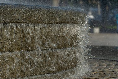 Movement transparent splash. Sparkling gush water of liquid drops detail. Fountain flows like of stream in the city in sunny weather. Refreshing cool water on hot day. Sprays in summertime close up.