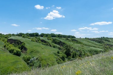 Yeşillikle kaplı vadi manzaralı. Jeolojik kusurları olan manzara vadisi. Yeryüzü dağları ve tümsekler gökyüzüne karşı rahatlıyor. Çıkıntıları ve aralıkları olan tepe kirişi. Ot ve ağaçlar bayır kanyonunda.