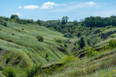 Yeşillikle kaplı vadi manzaralı. Jeolojik kusurları olan manzara vadisi. Yeryüzü dağları ve tümsekler gökyüzüne karşı rahatlıyor. Çıkıntıları ve aralıkları olan tepe kirişi. Ot ve ağaçlar bayır kanyonunda.
