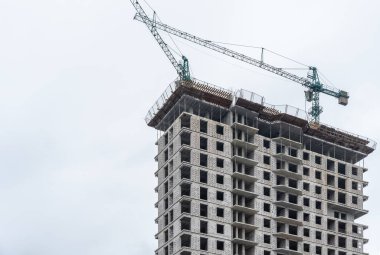 Endüstriyel inşaat vinçleri yeni modern binanın üzerinde çalışır. Köpük beton blok ve çakışmadan oluşan çok katlı bir mühendislik tasarımı. Pencereler ve balkonlar için yeri olan yüksek katlı bir daire.