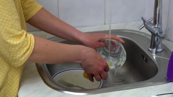 女性の手を黄色のスポンジ食器洗い機でシンクを閉じます 主婦は水道の下でボウルをきれいにします メイド掃除家事キッチン用品 家庭で食器を洗う — ストック動画