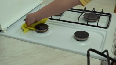 Gaz ocağını temizleyip düzenliyorum. Kadın elleri mutfakta sarı süngerle beyaz yüzeyi siler. Hizmetçi evde ocak yıkıyor. Ev işleri ve ev işleri. Mutfak temiz..