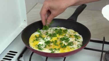 Maydanozu doğra ve soğanlı omlet pişir. Kızartma tavasında tavuk yumurtasıyla maydanoz ekleniyor. Protein, yumurta sarısı ve taze yeşil doğal beslenmedir. Ev mutfağı..