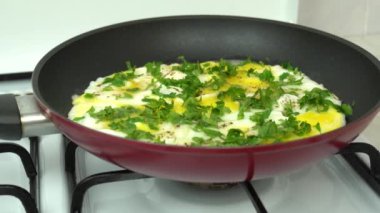 Maydanozu doğra ve soğanlı omlet pişir. Kızartma tavasında tavuk yumurtasıyla maydanoz ekleniyor. Protein, yumurta sarısı ve taze yeşil doğal beslenmedir. Ev mutfağı..