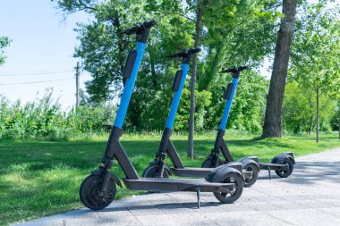Şehrin kaldırımına park edilmiş elektrikli scooter. Toplu taşıma kaldırımda duruyor. Çağdaş kentlerde kiralık ekonomik araç. Kiralık iş teknolojisi. Ekolojik nakliye. Boş zaman.