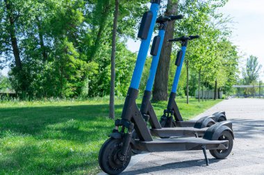 Şehrin kaldırımına park edilmiş elektrikli scooter. Toplu taşıma kaldırımda duruyor. Çağdaş kentlerde kiralık ekonomik araç. Kiralık iş teknolojisi. Ekolojik nakliye. Boş zaman.