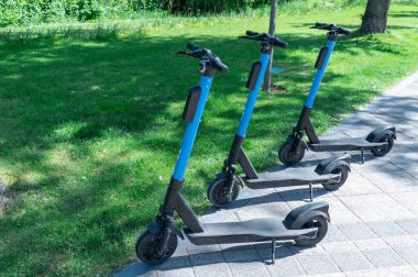 Şehrin kaldırımına park edilmiş elektrikli scooter. Toplu taşıma kaldırımda duruyor. Çağdaş kentlerde kiralık ekonomik araç. Kiralık iş teknolojisi. Ekolojik nakliye. Boş zaman.