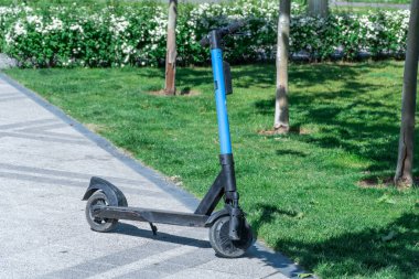Şehrin kaldırımına park edilmiş elektrikli scooter. Toplu taşıma kaldırımda duruyor. Çağdaş kentlerde kiralık ekonomik araç. Kiralık iş teknolojisi. Ekolojik nakliye. Boş zaman.