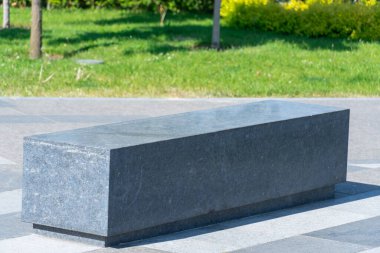Şehir parkında rahat bir taş bank. Boş zaman için gri sabit koltuk tasarımı. Dışarıdaki boş park tezgahı. Geometri doğa ve dinlenme yeri üzerine. Taş döşeli mobilyalar. Dekorasyon bahçede oturur.