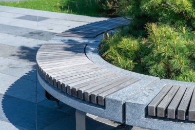 Şehir parkında taş ve ahşap tezgahta rahat. Boş vakitler için gri ve kahverengi koltukların tasarımı. Geometri doğa ve dinlenme yeri üzerine. Dışarıdaki boş park tezgahı. Bahçedeki mobilyalar..