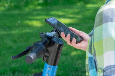 Cep telefonu olan kadın, elektrikli scooter kiralama için QR kodunu tarıyor. Akıllı telefonda limansız ulaşımı açmak için uygulamayı kullanan bir kadın. Kentsel tarzda ekolojik araç kullanmak. Modern teknolojiler.