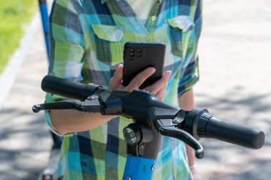 Cep telefonu olan kadın, elektrikli scooter kiralama için QR kodunu tarıyor. Akıllı telefonda limansız ulaşımı açmak için uygulamayı kullanan bir kadın. Kentsel tarzda ekolojik araç kullanmak. Modern teknolojiler.