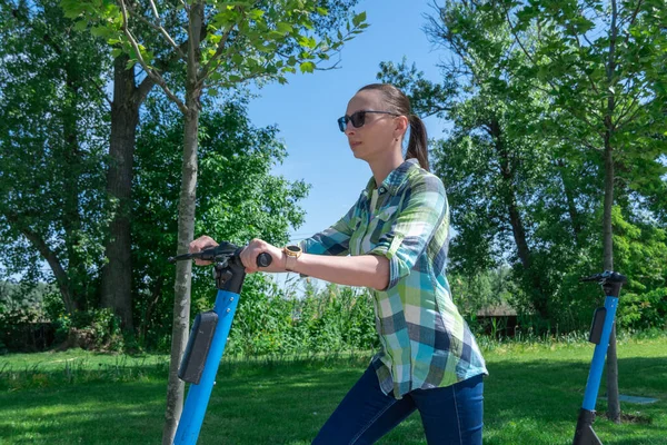 Tasasız kadın parkta kiralık elektrikli scooterla gezer. Rıhtımsız yolda giden genç bir yetişkin. Elektrikli araçta günlük kıyafetleri olan biri. Ekolojik seyahat ve macera.