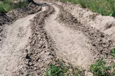 Ormandaki kum yolu. Garaj yolundaki dört tekerlekli bisikletin lastik izi. Doğa arazisindeki dörtlü bisikletin izi. Kum dokusu bozuk. Ormanda yol kapalı. Güneşli bir günde kum tepeleri ve yeşil orman.