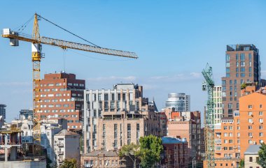 Gayrimenkul müteahhidi. Endüstriyel inşaat vinçleri yeni modern binanın üzerinde çalışır. Beton blok ve çakışmadan oluşan çok katlı mühendislik tasarımı. Yüksek katlı bir daire..