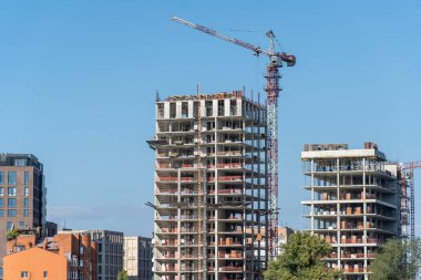 Gayrimenkul müteahhidi. Endüstriyel inşaat vinçleri yeni modern binanın üzerinde çalışır. Beton blok ve çakışmadan oluşan çok katlı mühendislik tasarımı. Yüksek katlı bir daire..