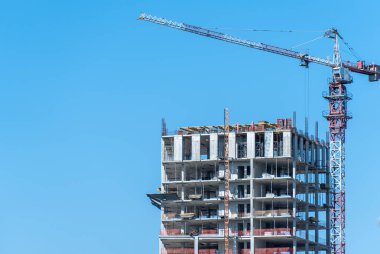 Gayrimenkul müteahhidi. Endüstriyel inşaat vinçleri yeni modern binanın üzerinde çalışır. Beton blok ve çakışmadan oluşan çok katlı mühendislik tasarımı. Yüksek katlı bir daire..