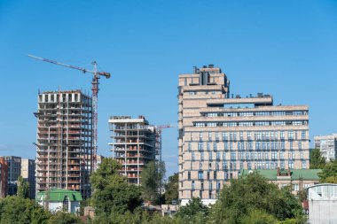 Gayrimenkul müteahhidi. Endüstriyel inşaat vinçleri yeni modern binanın üzerinde çalışır. Beton blok ve çakışmadan oluşan çok katlı mühendislik tasarımı. Yüksek katlı bir daire..