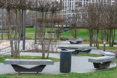 Yüksek katlı bankların çevrili olduğu güzel, modern bir şehir parkı. Şehir merkezindeki halka açık park. Kozalaklı kozalaklı kaldırım. Şehir manzarasında dinlenmek için bir yer. Şehir mimarisi.