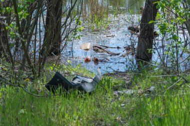 Ormandaki çöplük nehre saçılmış. Piknikten sonra gölde plastik çöp. İnsanlar yasadışı olarak çöp atıyor. Çevre koruma ile ilgili dünya ekolojisi problemi. Doğadaki çöp yığını.