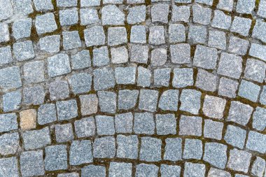 Natural stone background and texture in gray color close up. Pavement paved with square and uneven stones. Paving street with pattern. Between crushed cobblestones there are earth sand and grass. clipart