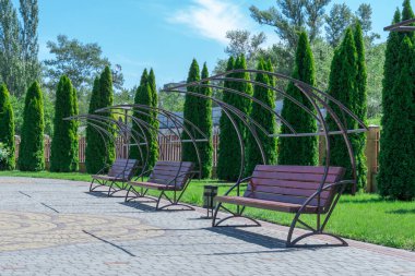 Parkta sıra sıra dizilmiş boş ahşap banklar. Sabit bir dinlenme yeri ve rahat bir koltuk. Kaldırımın kenarında boş duruyor. Yürüyüş ve dinlenme için güzel bir yer. Modern rahatlama nesnesi.