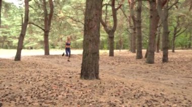 Yetişkin kadın kardiyo sporu yapıyor ve kozalaklı ormanda koşuyor. Fitness kızlarının sağlık koşusu açık havada eğitimdir. Koşu antrenmanı ve sağlıklı yaşam tarzı kavramı. Atletik genç yetişkin yolu.