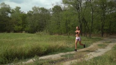 Yetişkin kadın kardiyo sporu ve sazlıkta koşuyor. Fitness kızlarının sağlık koşusu açık havada eğitimdir. Koşu antrenmanı ve sağlıklı yaşam tarzı kavramı. Atletik genç yetişkin yolu.