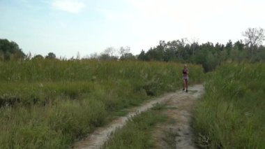 Yetişkin kadın kardiyo sporu ve sazlıkta koşuyor. Fitness kızlarının sağlık koşusu açık havada eğitimdir. Koşu antrenmanı ve sağlıklı yaşam tarzı kavramı. Atletik genç yetişkin yolu.