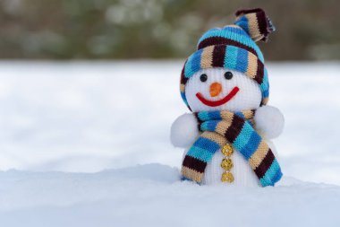 Noel kıyafetleri içindeki kardan adam kış ormanında beyaz karın üzerinde duruyor. Takı örülmüş. Noel ve yeni yıl dekorasyonu. Tasarım için bir şablon. Kış mevsiminin sembol xmas.