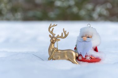 Oyuncak Noel Baba ya da Ted Moroz Noel kıyafetleriyle beyaz karda altın geyiğe biniyor. Xmas ve yeni yıl dekorasyonu. Tasarım için bir şablon. Şenlikli kış mevsiminin peri masalı.