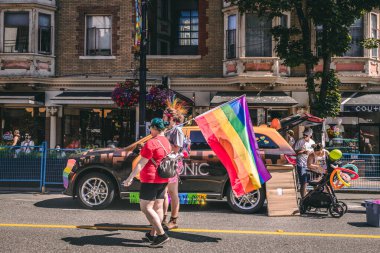 Vancouver, Kanada - 31 Temmuz 2022: Onur Yürüyüşü sırasında insanlar Robson Caddesi 'nde gökkuşağı bayrağıyla yürüyorlar