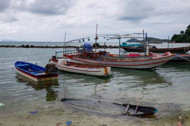 Tayland 'ın Ko Samui kıyısındaki sığ sularda yüzen balıkçı tekneleri görünür enkazlarla dolu.