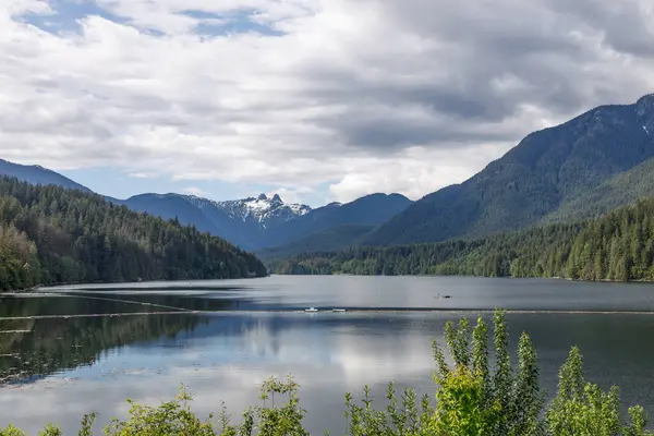 Capilano Reservoir 'un sakin manzarası. Arka planda görkemli Aslanlar Tepeleri var.