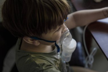 A young child using a nebulizer mask for asthma and respiratory treatment, highlighting the importance of pediatric care in managing respiratory conditions clipart