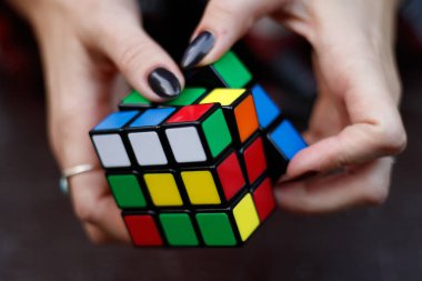 Vancouver, Kanada - 12019 Ekim: Renkli bir Rubik küp bulmacasını karanlık arka plana karşı manipüle eden eller