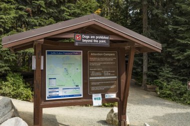 British Columbia, Kanada - 24 Ağustos 2022: Joffre Lakes İl Parkı 'nda park haritası, kamp yönetmelikleri ve kahverengi ahşap barınak altında 