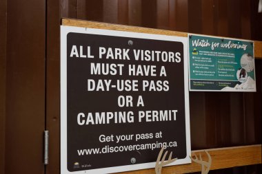 British Columbia, Kanada - 24 Ağustos 2022: Park girişi tabelasında ziyaretçilerin günlük kullanım izni veya kamp iznine sahip olmaları gerektiği ve arka planda Wolverine farkındalığı olduğu belirtiliyor