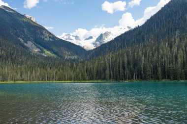 Aşağı Joffre Gölü turkuaz buzul sularını gözler önüne seriyor. Etrafı sürekli yeşil ormanlar ve mavi yaz gökyüzü altında karla kaplı dağ zirveleriyle çevrili.