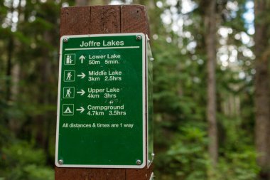 Joffre Gölleri 'nin yol işareti aşağı, orta, yukarı göllere ve tahta direğe monte edilmiş kamp alanlarına olan mesafeleri ve yürüyüş zamanlarını gösteriyor
