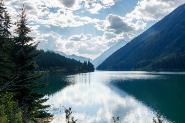 Duffey Gölü 'nün sakin sulara yansıyan dramatik bulutları ormanlarla kaplı dağ yamaçları ve güneşli gökyüzüyle çevrili.