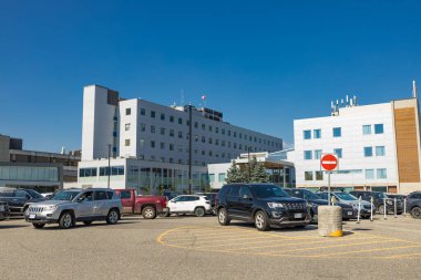 Prens George, Kanada - 25 Ağustos 2022: Kuzey BC Üniversite Hastanesi Dış görünümü güneşli bir günde otoparkla dolu beyaz çok katlı binayı gösteriyor