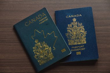 Vancouver, Kanada - 18 Mart 2025: Ahşap bir yüzeye yerleştirilmiş iki Kanada pasaportu, tasarımın evrimini gözler önüne seriyor