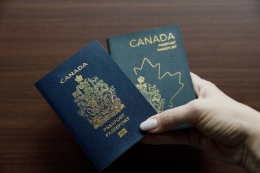 Vancouver, Kanada - 18 Mart 2025: Tasarımın evrimini gösteren iki Kanada pasaportunu yan yana tutmak