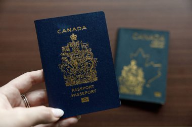 Vancouver, Kanada - 18 Mart 2025: Koyu mavi bir Kanada pasaportu, üzerinde akçaağaç yaprağı ana hatları ve arması bulunan, tasarımın evrimini gözler önüne seren, altın işlemeli bir Kanada pasaportu