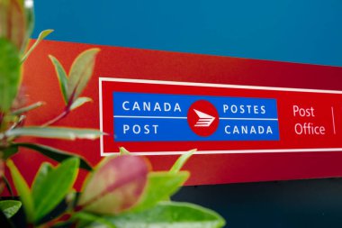 Vancouver, Kanada - 21 Haziran 2025: Kanada Postane tabelası iki dilli, mavi ve kırmızı zemin üzerine kurulmuş