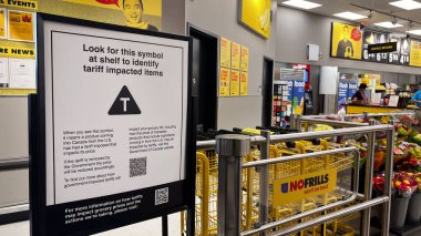 Vancouver, Kanada - 24 Temmuz 2025: Canlı bir No Frills mağazasının içinde, ABD 'nin Kanada ile ticaret savaşının ortasında ithalatından gelen fiyat değişikliklerine dikkat çeken T sembollü gümrük vergisi taşıyan bir tabela var