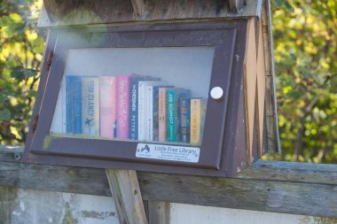 Vancouver, Kanada - 15 Eylül 2025: Renkli kitaplarla dolu camdan önü açık küçük bir kütüphane