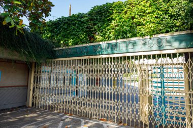 Vancouver, Kanada - 15 Eylül 2025: Kitsilano Yüzme Havuzu girişindeki kapalı metal kapı, gür sarmaşıklar ve açık gökyüzü altındaki ağaçlarla çevrili